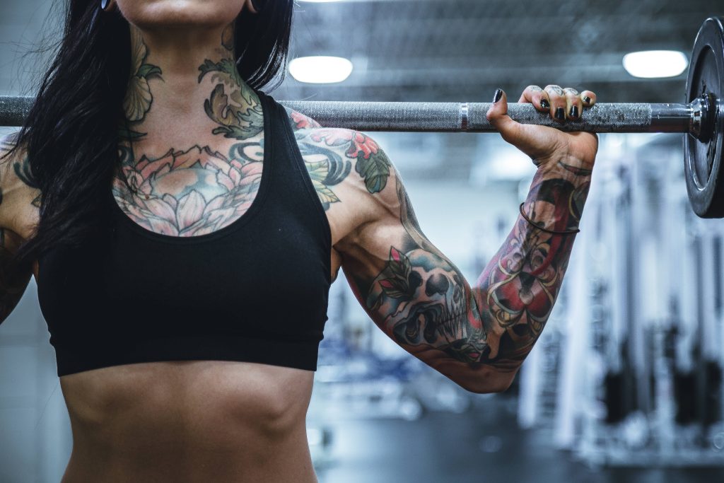 Muscular tattooed woman weightlifting in gym fitness wallpaper for strength training motivation
