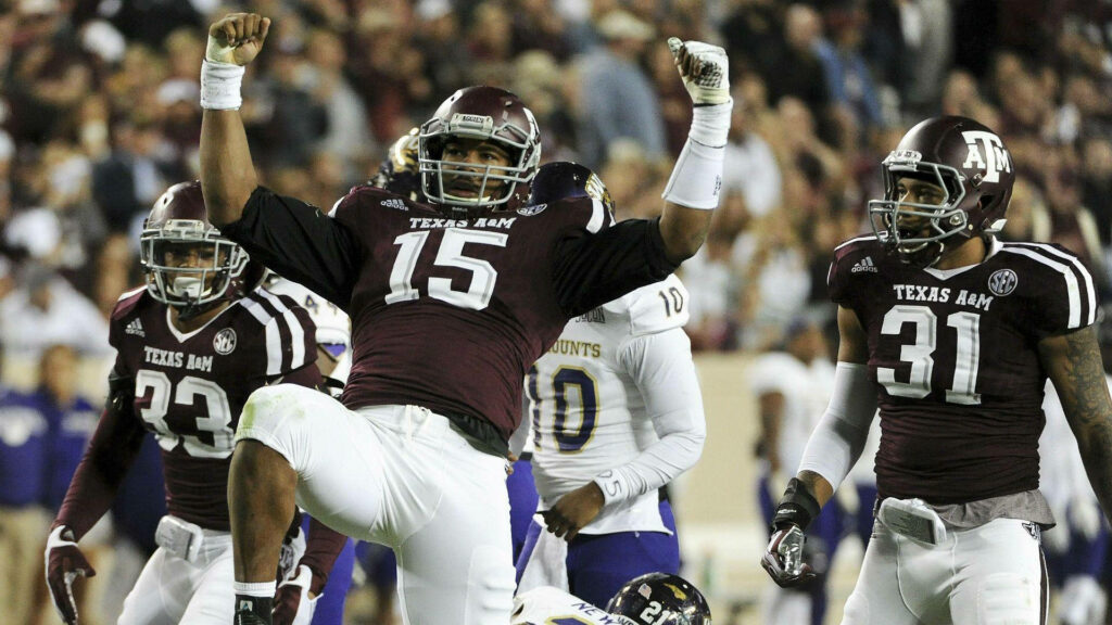 Myles Garrett Texas A&M football player number 15 raising hands in intense game action wallpaper