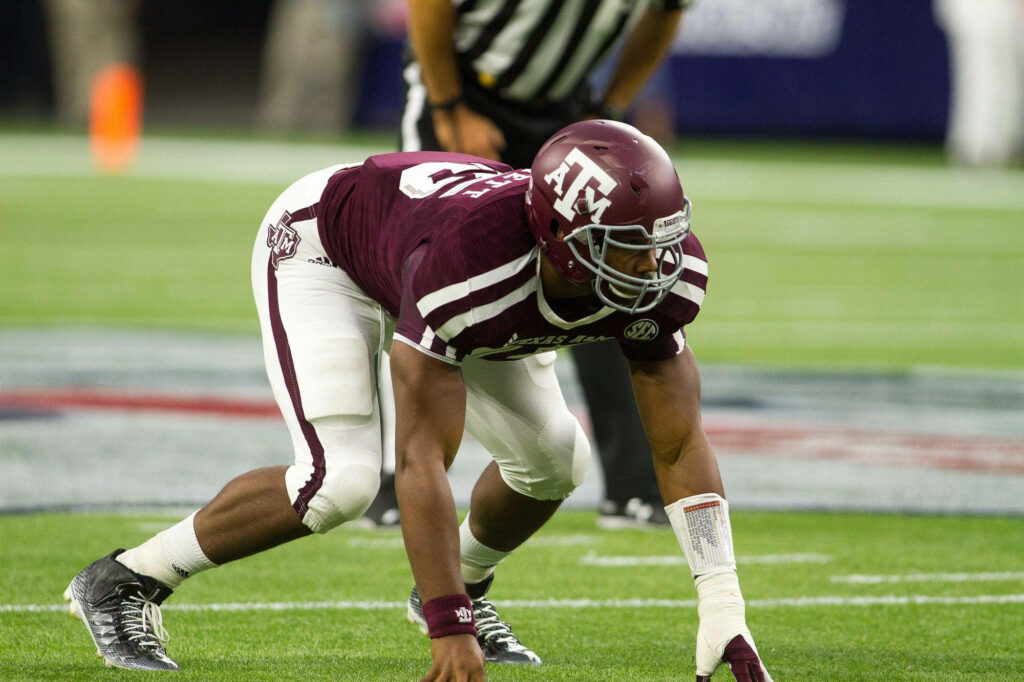 Myles Garrett in Texas A&M uniform crouching on football field showing intense focus and athleticism Wallpaper