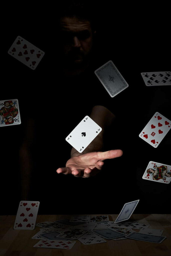 Mysterious figure tossing red and black playing cards in dark casino nightlife wallpaper background
