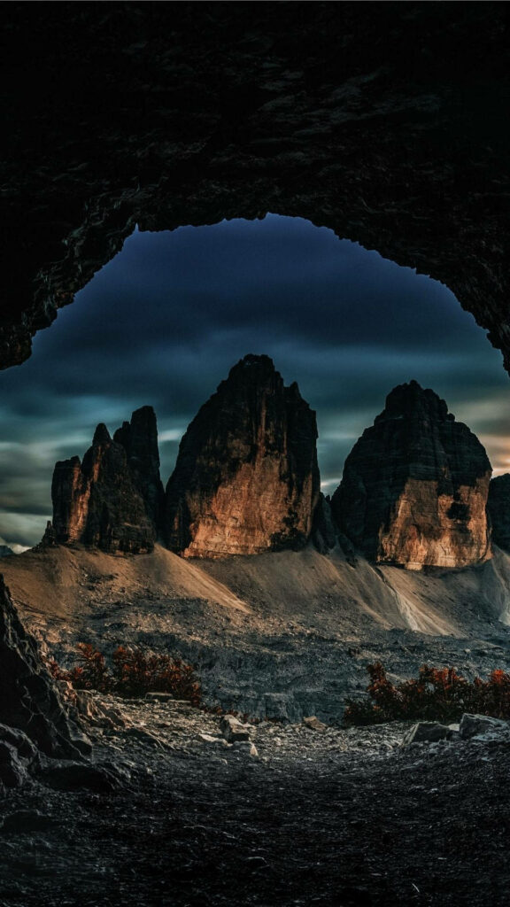 Rocky Cave View: Dramatic Mountains Under Moody Skies Wallpaper