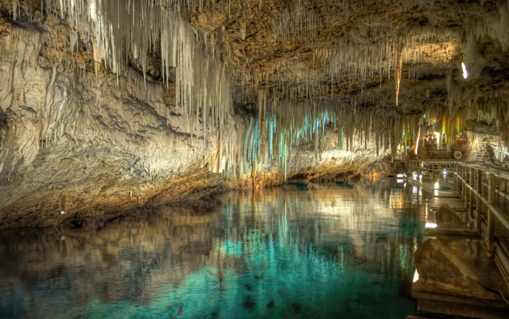 Enigmatic Cave Wallpaper: Stalactites & Turquoise Water Reflection