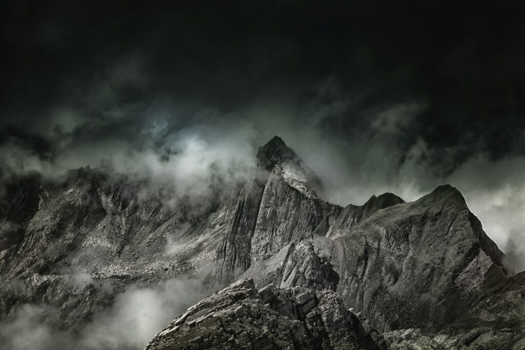 Foggy jagged mountain peaks with dark rugged rocks creating a mysterious atmospheric wallpaper