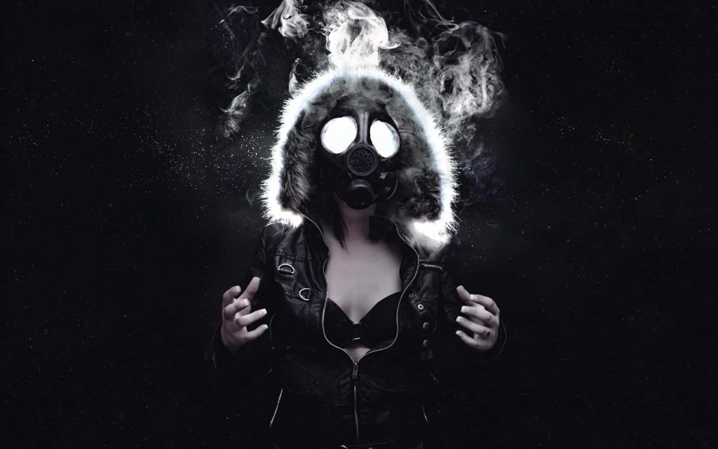 Mysterious figure in tactical gas mask with fur hood in dark smoky post-apocalyptic scene Wallpaper