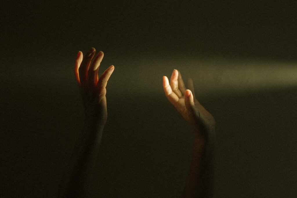 Hands Reaching for Light: Mysterious Dark Background Wallpaper
