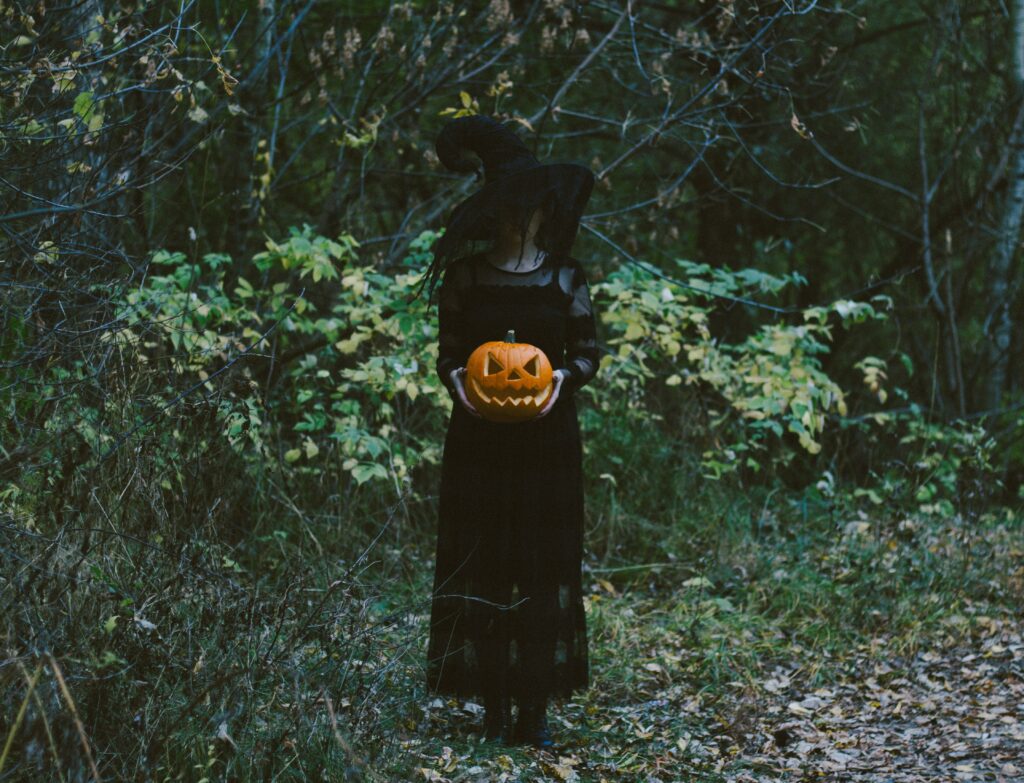 Mysterious Witch with Pumpkin in Eerie Forest Wallpaper - Halloween Vibes