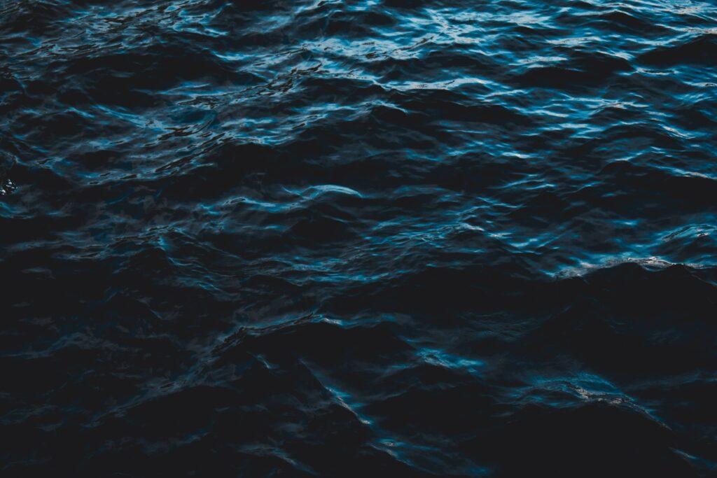 Dark blue sea surface with intricate ripples and gentle waves creating a serene aquatic wallpaper
