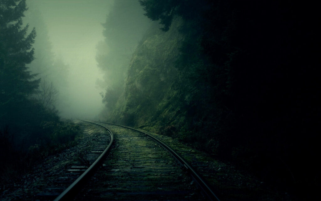 Misty Trails: Serene 4k Nature Background Illustrating Enchanting Train Tracks Amidst Eerie Fog and Verdant Forest Wallpaper