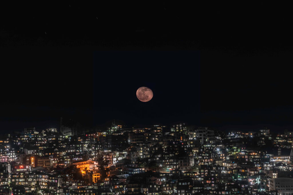 Luminous Midnight: An HD Wallpaper capturing the Enchanting Glow of a Full Moon over a Night City