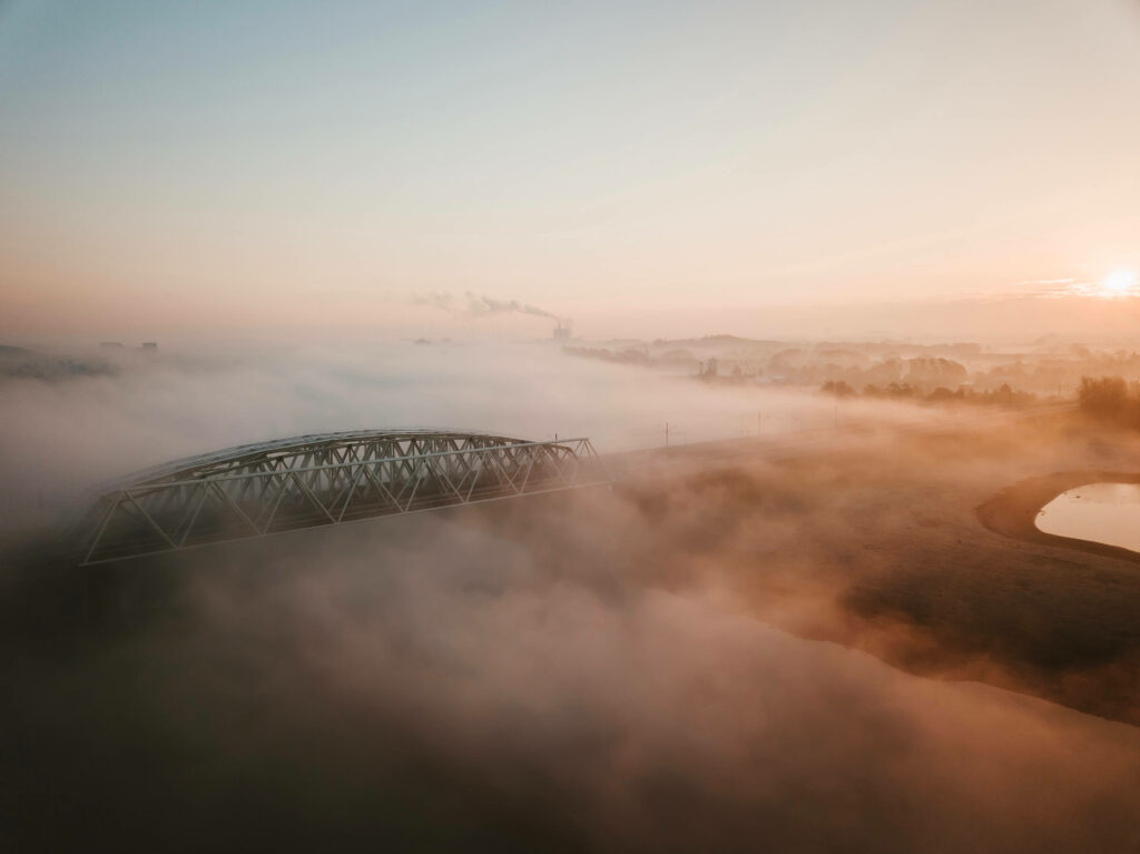 Majestic Sunset Bridge Embraced by Enigmatic Smoke-Laden Haze Wallpaper