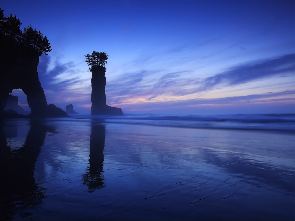 Dramatic Japanese coastal rock formation with natural arch at twilight foggy sea and colorful sky Wallpaper