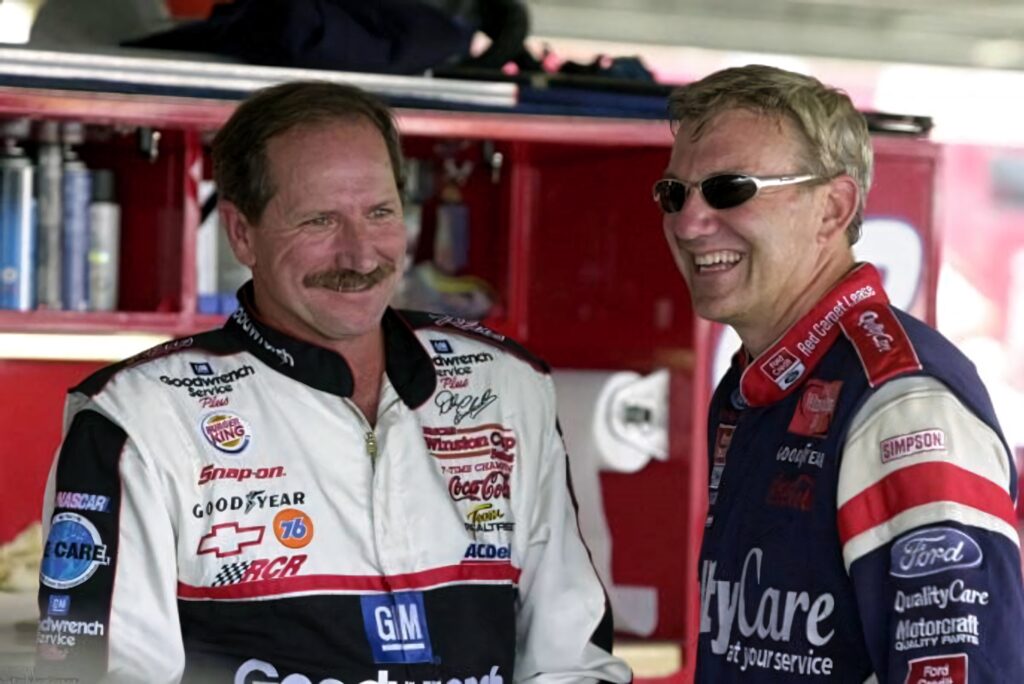 NASCAR legends Dale Earnhardt Sr and Dale Jarrett smiling in vibrant racing suits garage wallpaper