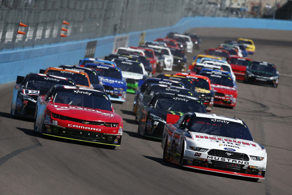 NASCAR race cars speeding closely on racetrack intense high stakes race thrilling convoy wallpaper