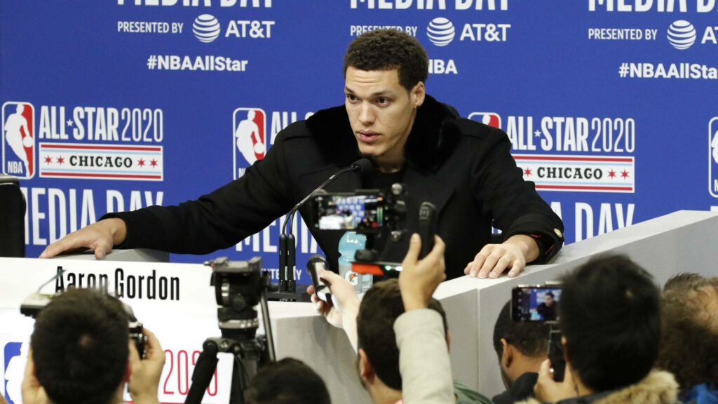 NBA athlete Aaron Gordon speaks at 2020 NBA All-Star Media Day surrounded by journalists and photographers Wallpaper