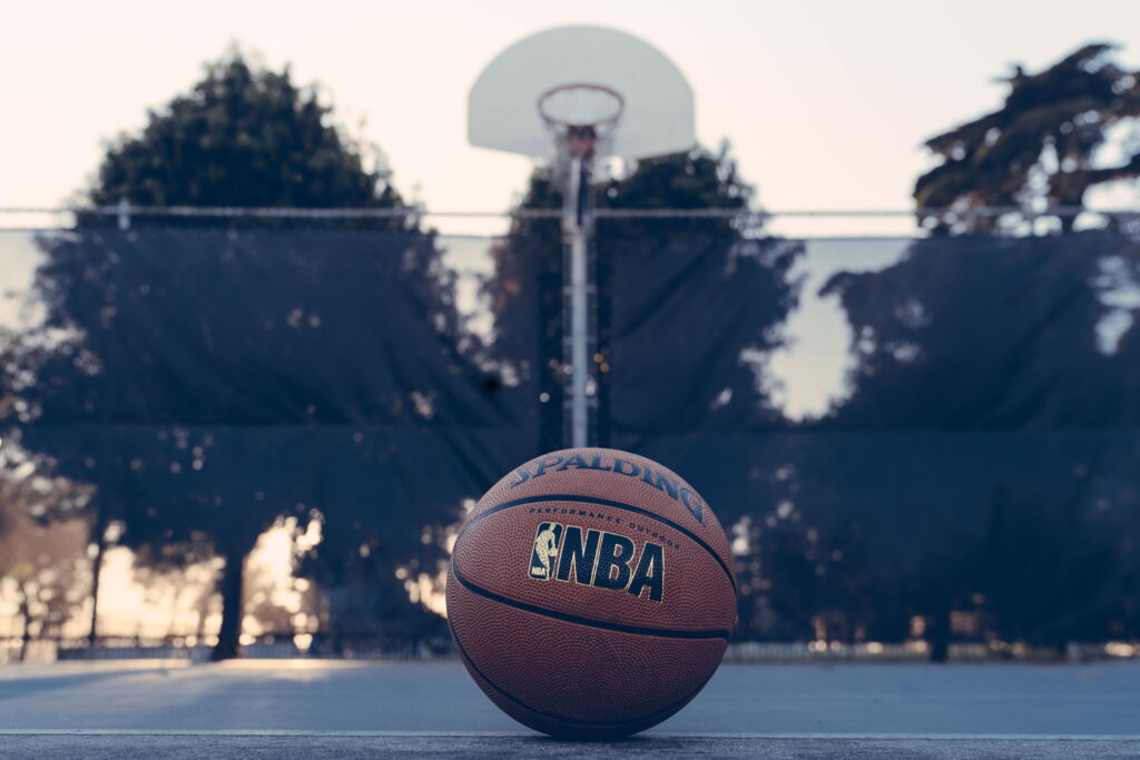 Spalding NBA basketball on outdoor court at golden hour with soft sunlight and blurred hoop Wallpaper