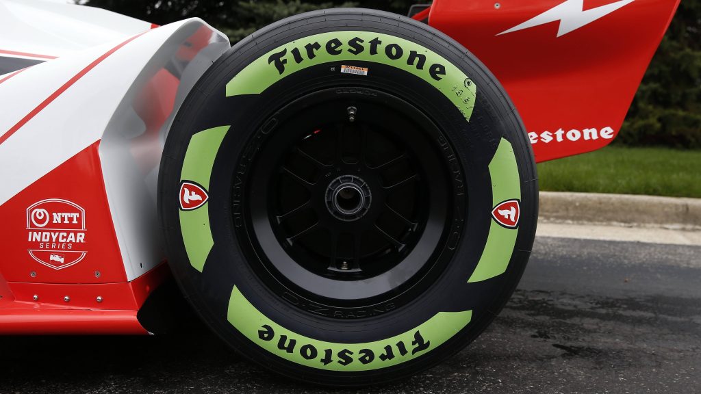 Close-up of Firestone tire with green sidewall on black OZ Racing wheel and red white racecar Wallpaper
