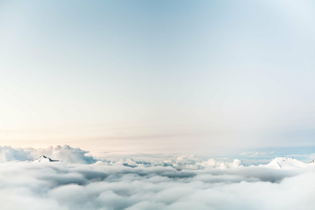 Majestic mountain peaks above soft pastel clouds sky serene nature wallpaper background
