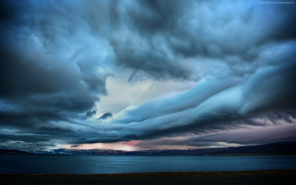 Dramatic storm clouds over calm dark coastal waters moody blue gray landscape wallpaper