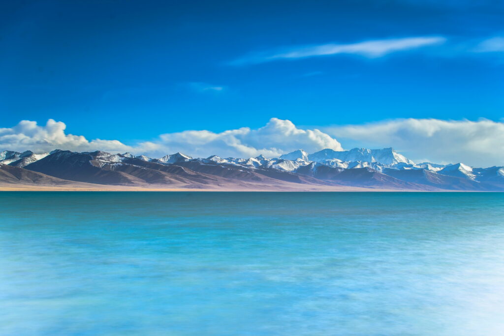 Serene turquoise lake with snow-capped mountains under vibrant blue sky nature wallpaper