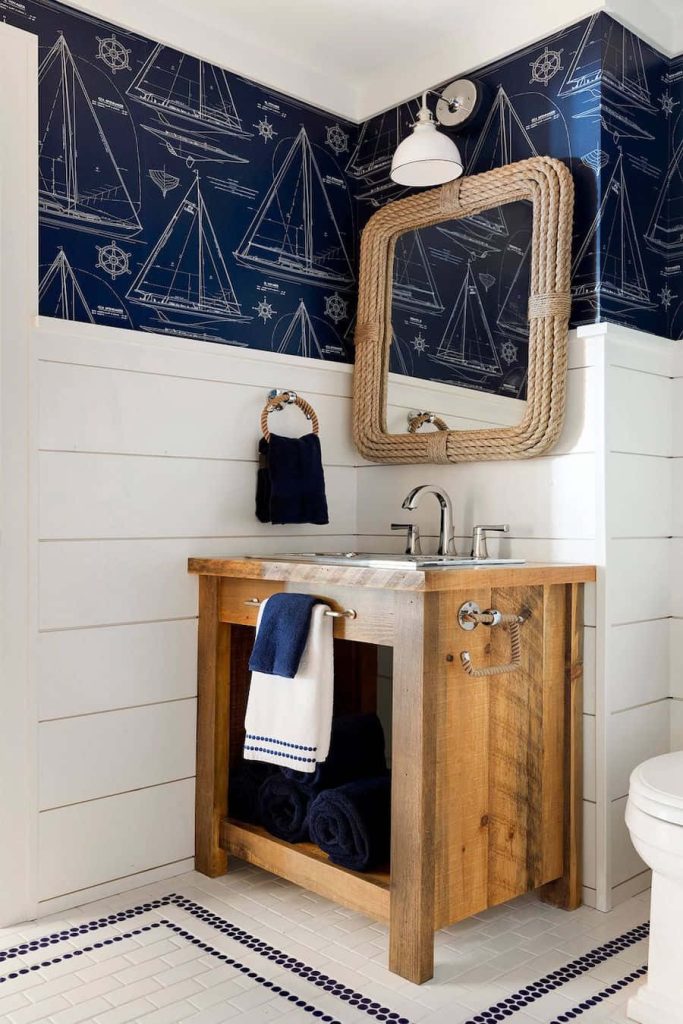 Coastal bathroom with blue sailboat wallpaper rustic wood vanity and rope-framed mirror design