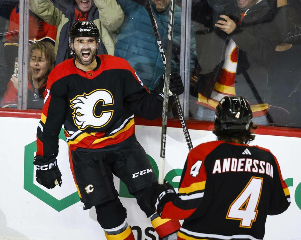 Nazem Kadri and Rasmus Andersson celebrate on ice in Calgary Flames uniforms with fans cheering Wallpaper