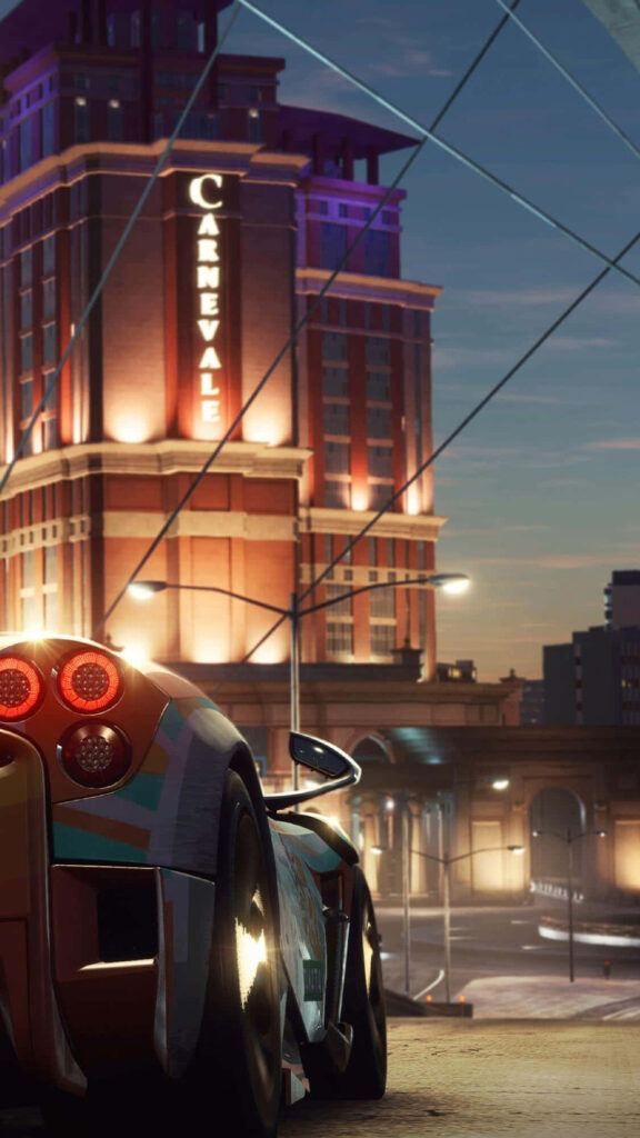 High-performance sports car with glowing rear lights parked by illuminated Carnevale building at dusk Wallpaper