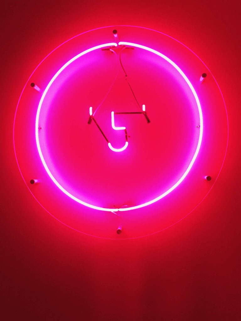 Glowing neon abstract face with L shape and smile in circular frame on red background wallpaper