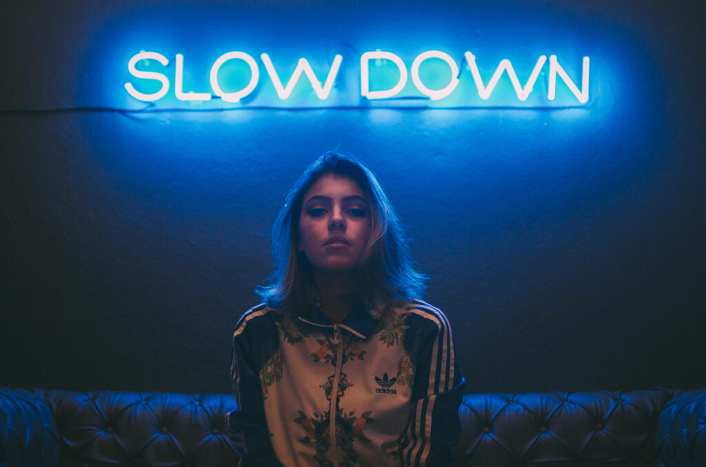 Neon Aesthetic Wallpaper: Girl Under 'SLOW DOWN' Sign