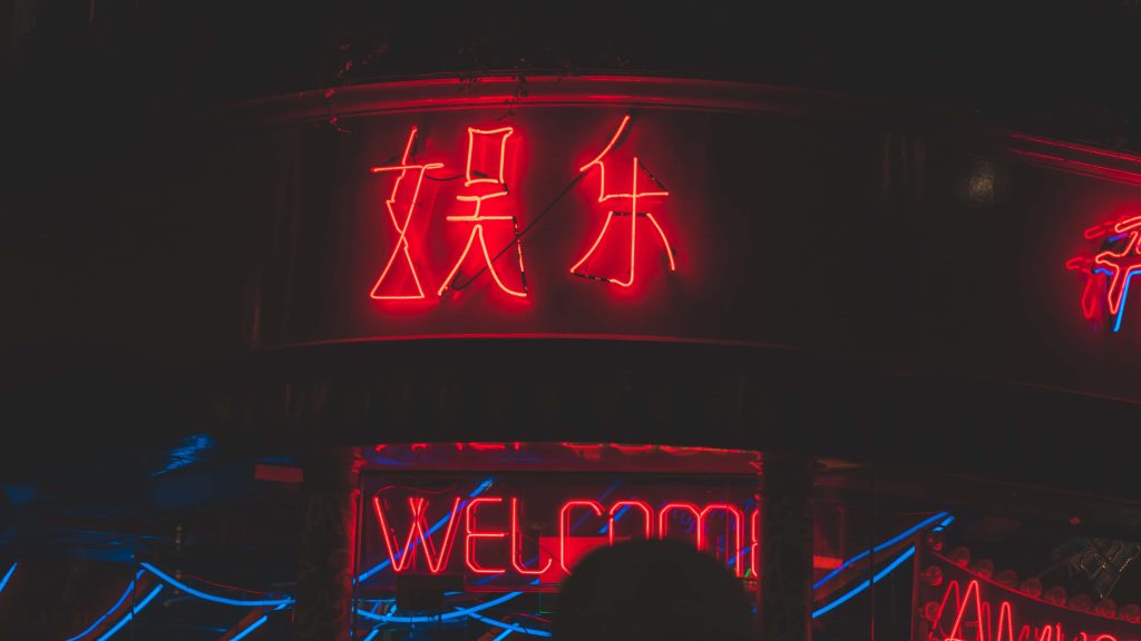 Neon red Chinese entertainment sign and welcome glowing on dark building in cyberpunk style Wallpaper