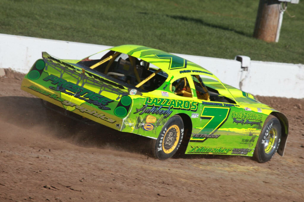 Neon green yellow number 7 dirt race car drifting on dust rugged track vibrant stock car wallpaper
