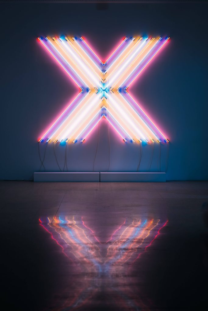 Neon letter X wallpaper with glowing pink blue white tubes and reflective polished floor background