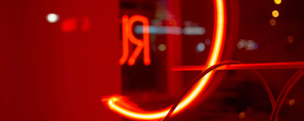Radiant Neon Glow: A Captivating Red Ultra Wide HD Wallpaper with Inverted 'R' Reflection on Glass