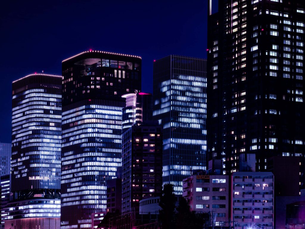 Neon night cityscape wallpaper with illuminated skyscrapers under deep blue evening sky