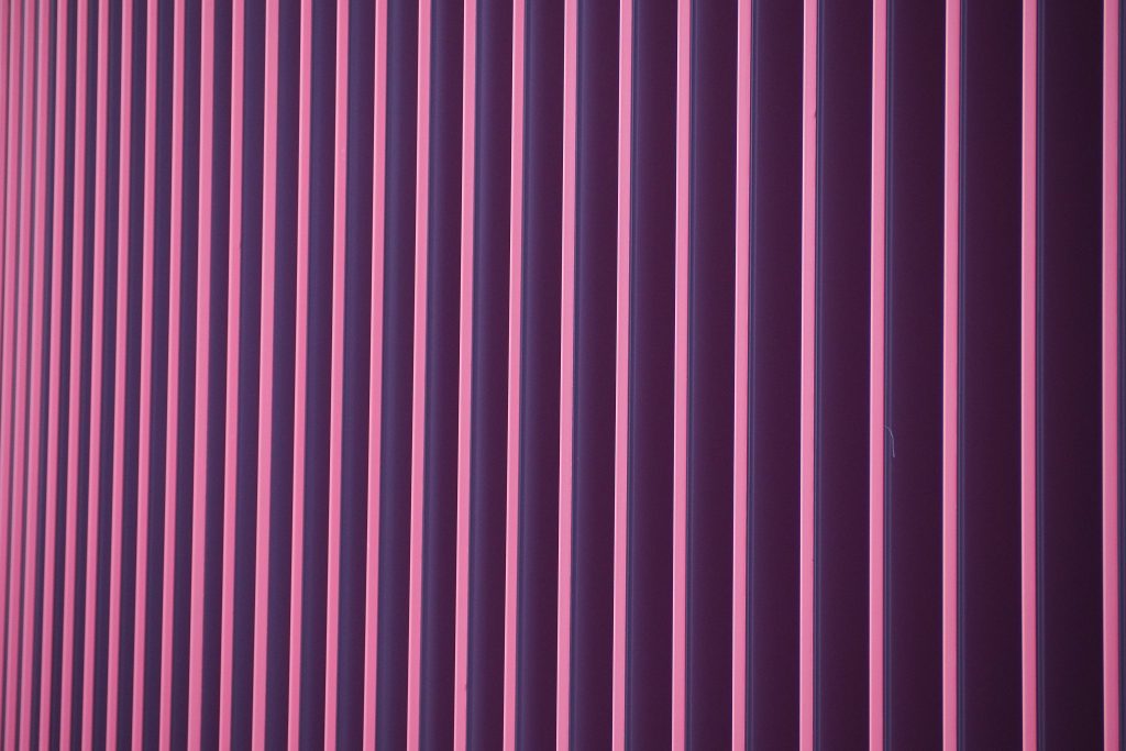 Neon pink and deep purple 3D striped geometric wallpaper with vertical minimalist design background