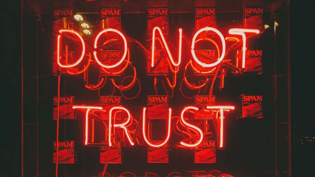 Neon red DO NOT TRUST sign glowing over dark background with grid of SPAM cans wallpaper
