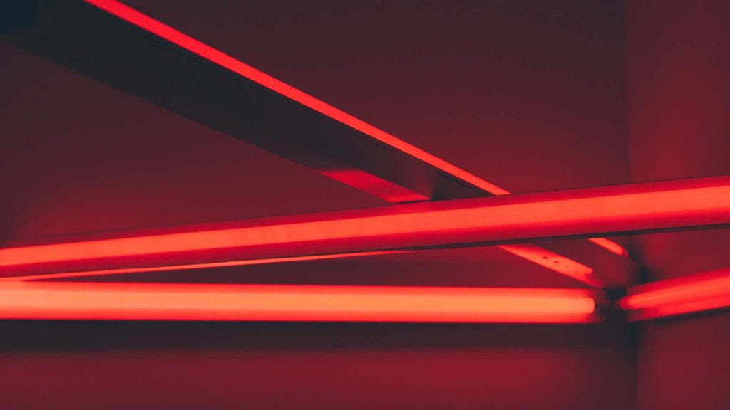 Vibrant glowing red neon tubes in angular geometric design on dark red background wallpaper