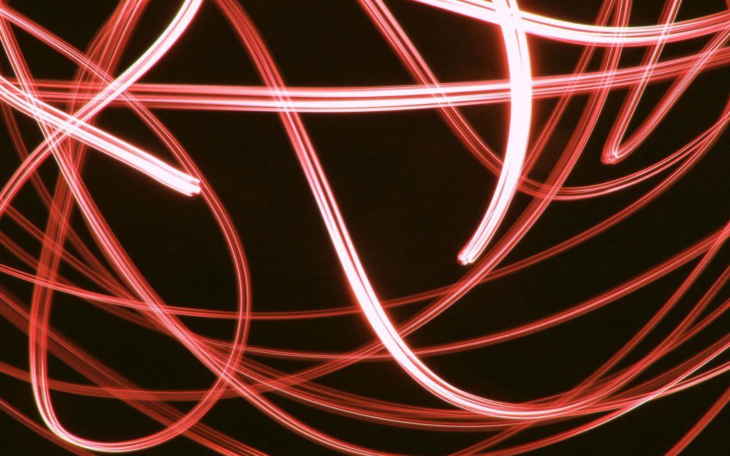 Abstract neon red light trails on black background dynamic motion long exposure wallpaper