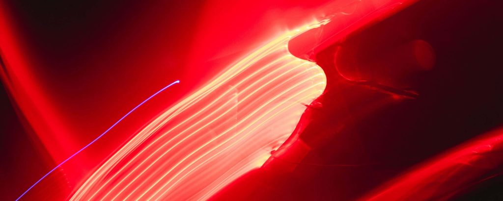 Ultra wide wallpaper with vibrant neon red light trails long exposure abstract background