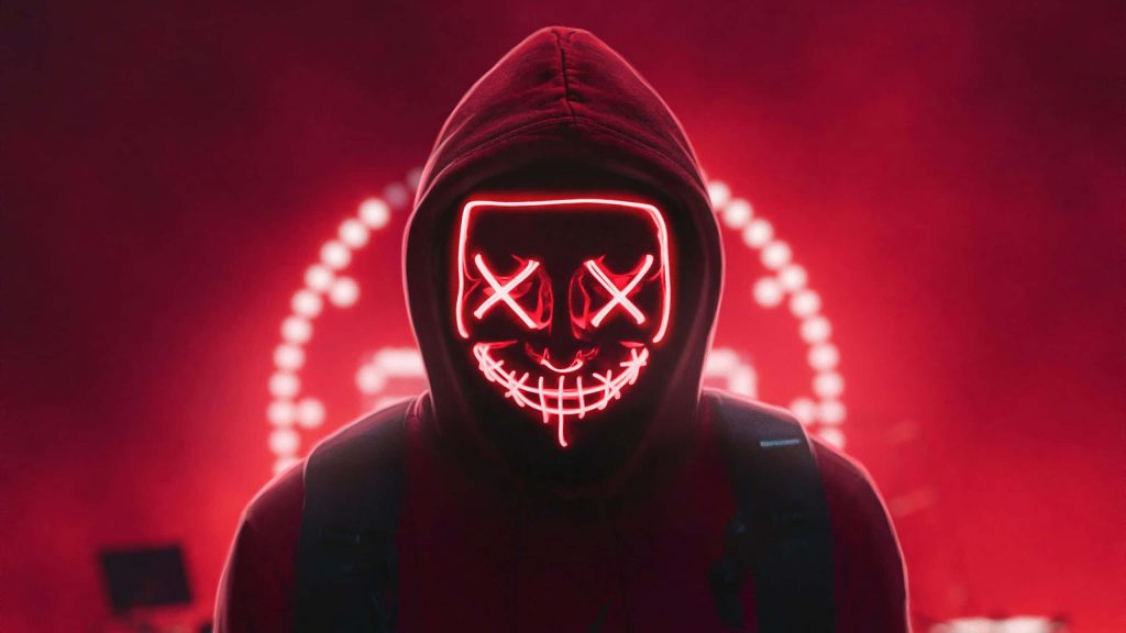 Mystery hooded figure with glowing neon red Purge mask on vibrant neon red bokeh background Wallpaper