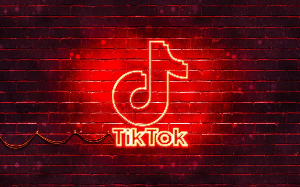 Vibrant red TikTok logo neon sign on dark brick wall glowing digital art wallpaper background