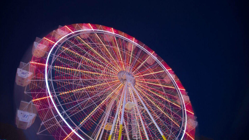 Ferris Wheel Enchantment: Neon Lights Illuminating the Night Sky in Captivating Time-Lapse Shot Wallpaper