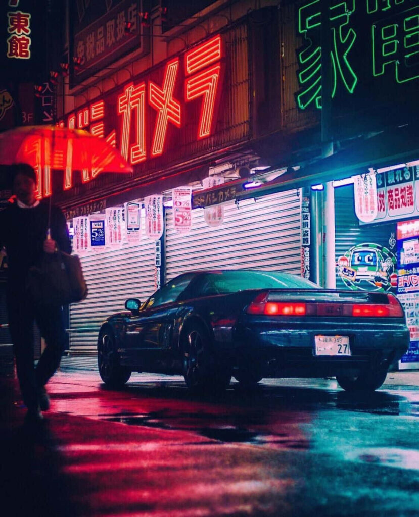 Sleek sports car gleaming under neon lights on rainy city street capturing vibrant street racing energy Wallpaper