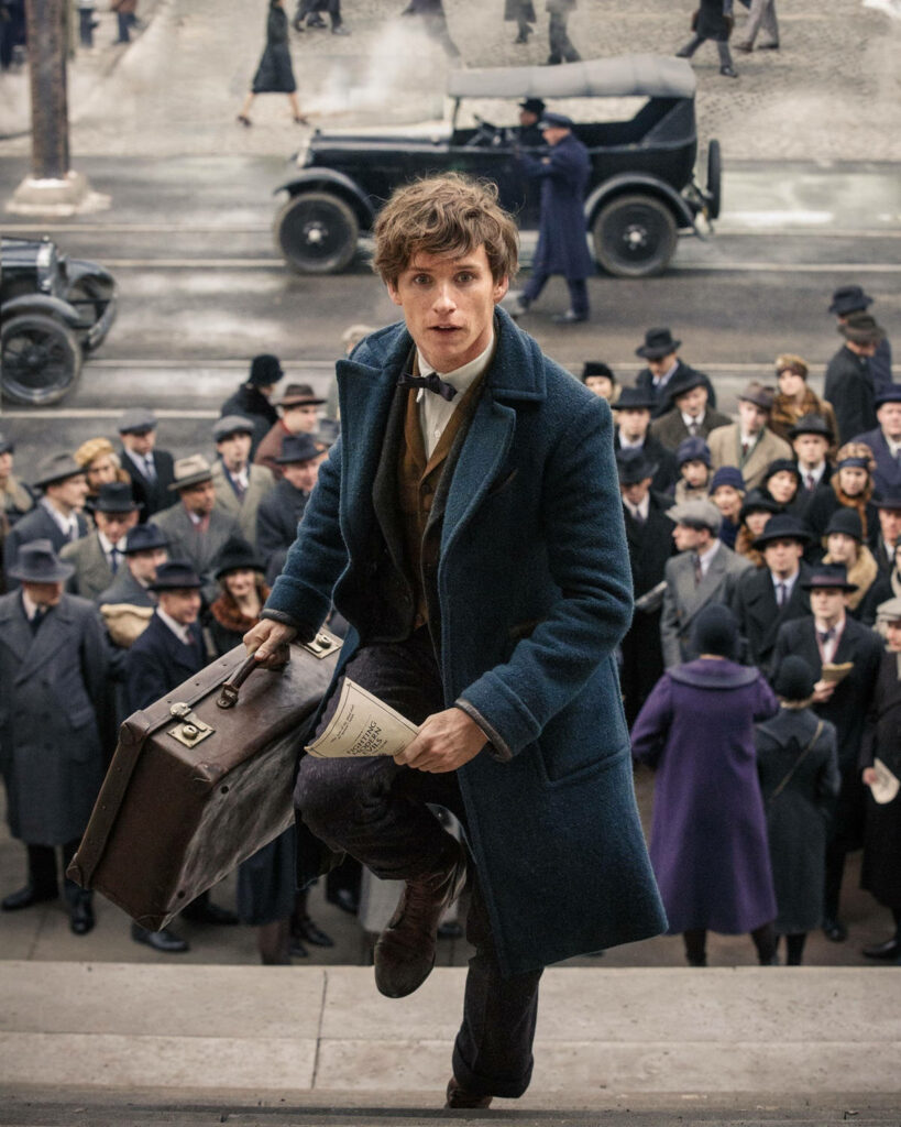 Newt Scamander climbing steps with suitcase in 1920s city Fantastic Beasts wallpaper background