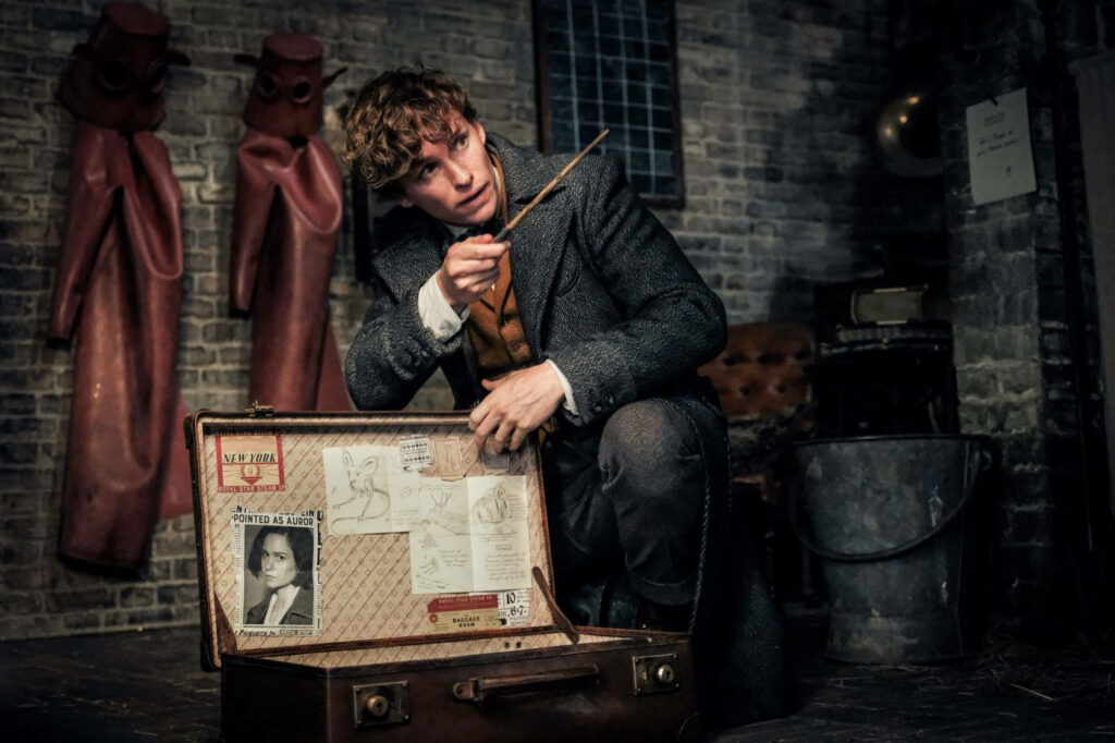 Newt Scamander opens magical briefcase revealing sketches and documents in dimly lit room wallpaper