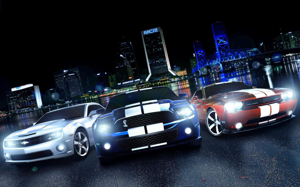 Three sleek muscle cars with racing stripes parked on a vibrant city street at night skyscrapers Wallpaper