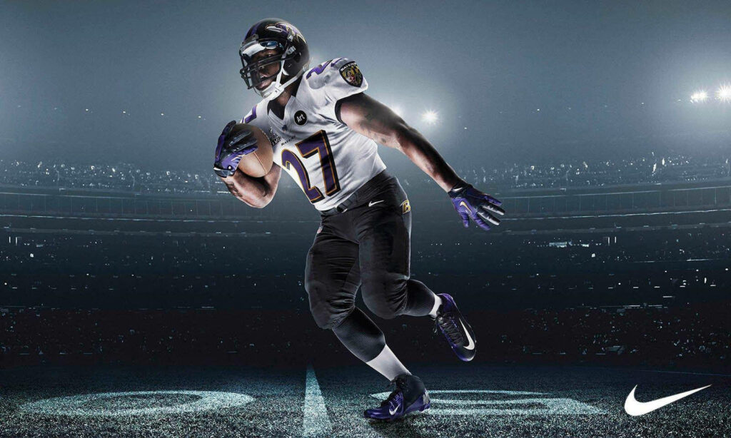 Night Game Rush: NFL Star Sprints Through Illuminated Stadium Wallpaper in HD 1600x960 Resolution