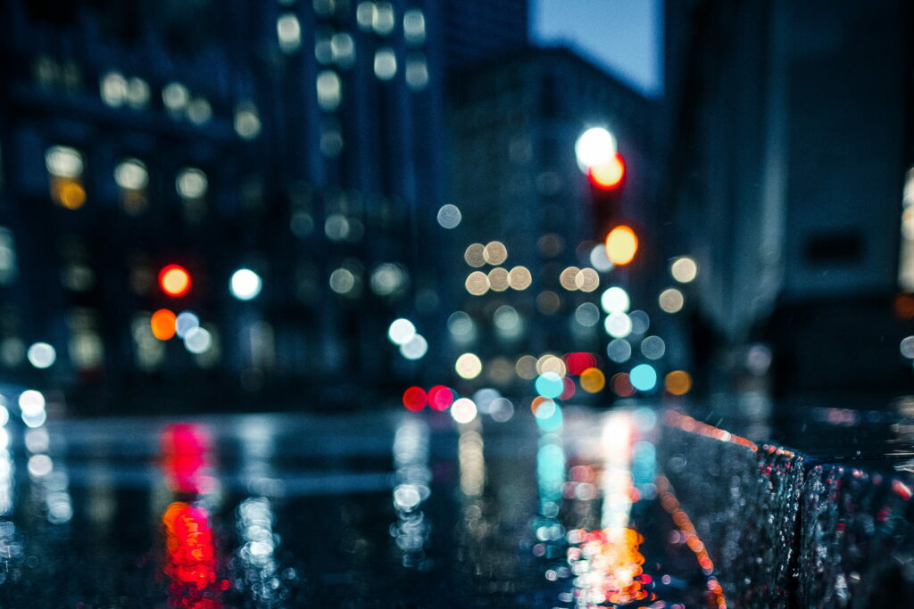4K rain-soaked city street at night with vibrant bokeh lights on wet pavement wallpaper