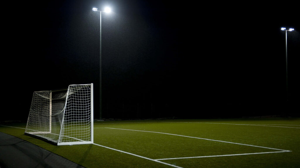 The Enigmatic Glow: A Captivating View of a Nighttime Football Haven Wallpaper