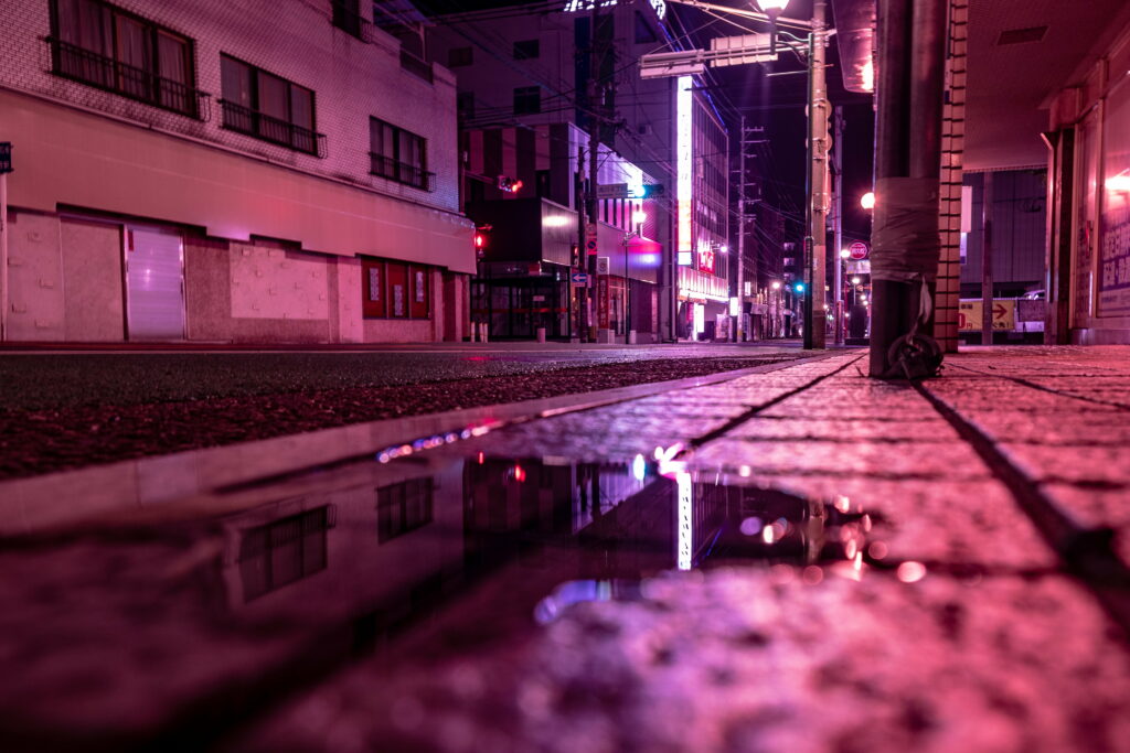Glistening Urban Nightscape: Neon-lit Streets Reflected in Puddled Splendor Wallpaper