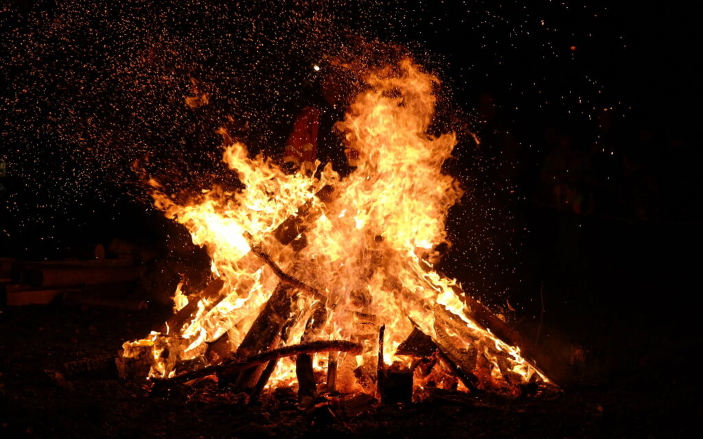 HD bonfire flames glowing orange and gold against night creating a warm cozy background wallpaper